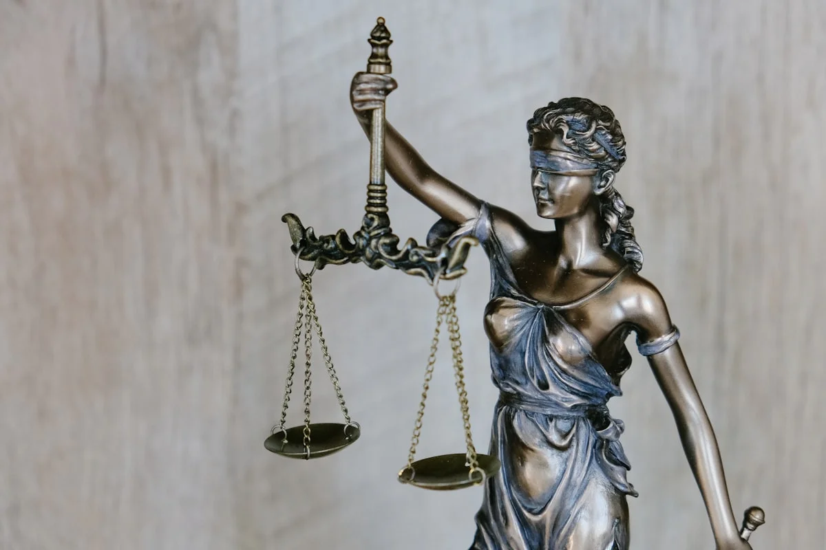 A wooden legal gavel resting on a sound block with law books in the background